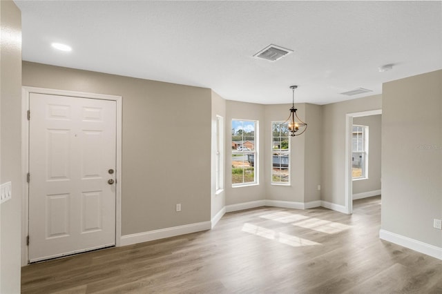 foyer entrance featuring baseboards, visible vents, and wood finished floors