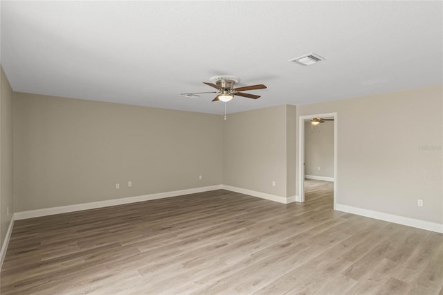 empty room with baseboards, ceiling fan, visible vents, and wood finished floors