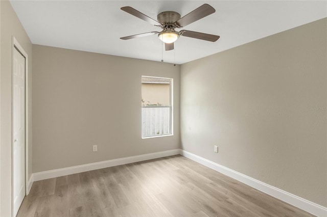 spare room featuring a ceiling fan, light wood-style flooring, and baseboards