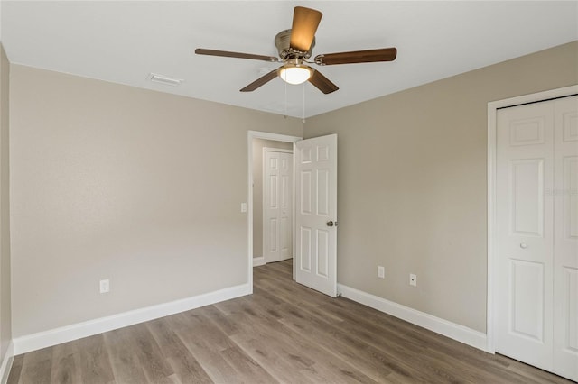 unfurnished bedroom featuring a closet, wood finished floors, a ceiling fan, and baseboards