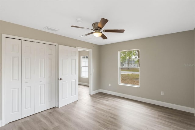 unfurnished bedroom with light wood finished floors, a closet, visible vents, and baseboards