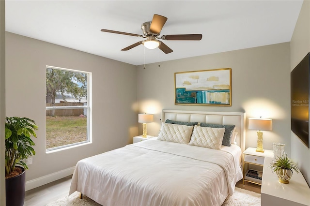 bedroom with a ceiling fan, baseboards, and wood finished floors