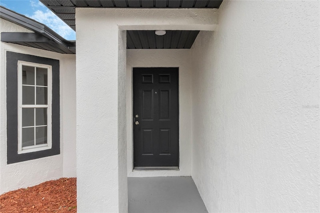 doorway to property featuring metal roof and stucco siding