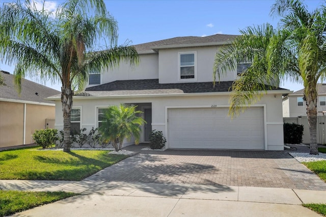 view of front of home with a garage, a front yard, decorative driveway, and stucco siding