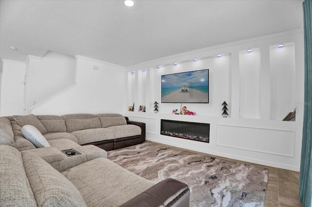 living area featuring a glass covered fireplace and crown molding