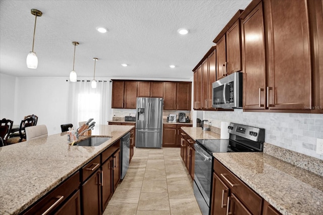 kitchen featuring stainless steel appliances, a sink, light stone countertops, tasteful backsplash, and decorative light fixtures