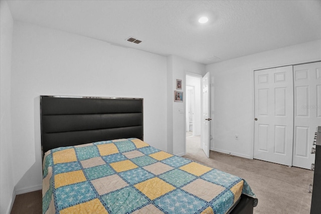 bedroom with a textured ceiling, carpet, visible vents, and baseboards