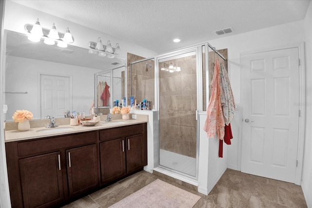 full bath with double vanity, a shower stall, visible vents, and a sink