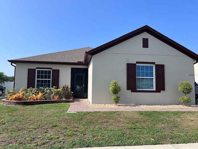 single story home featuring roof with shingles, a front lawn, and stucco siding