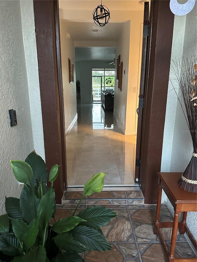 hallway with a textured wall and baseboards