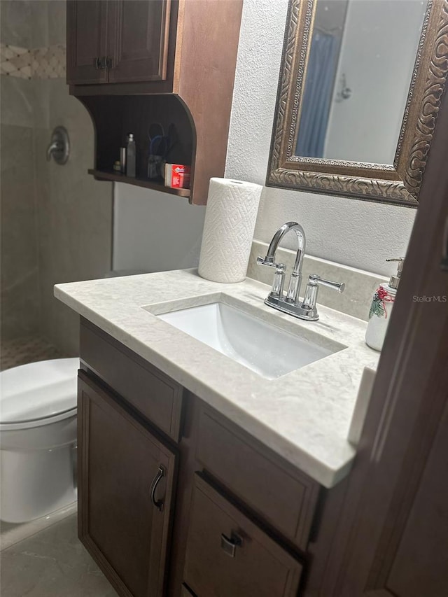 full bathroom with toilet, a textured wall, tiled shower, and vanity