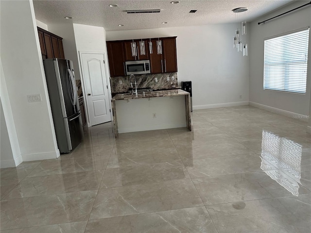 kitchen with stainless steel appliances, tasteful backsplash, an island with sink, dark stone counters, and baseboards