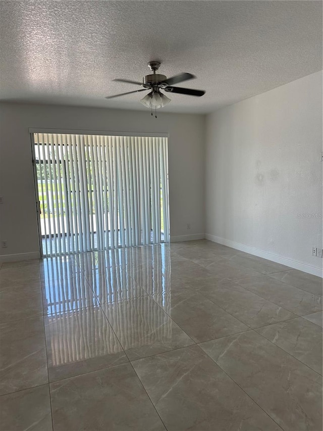 unfurnished room with a ceiling fan, a textured ceiling, and baseboards