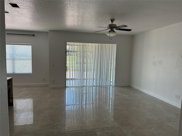 spare room with ceiling fan, baseboards, and a textured ceiling