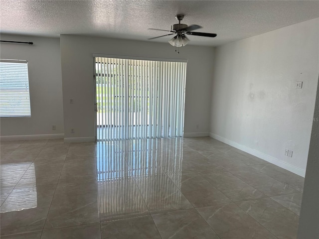 spare room with a ceiling fan, a textured ceiling, and baseboards