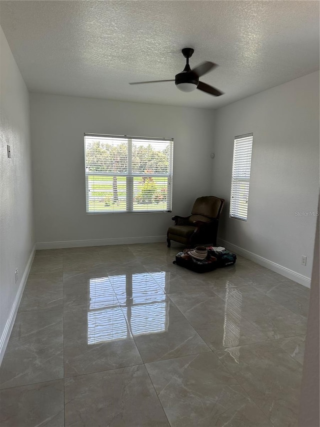 unfurnished room featuring a ceiling fan, a textured ceiling, and baseboards