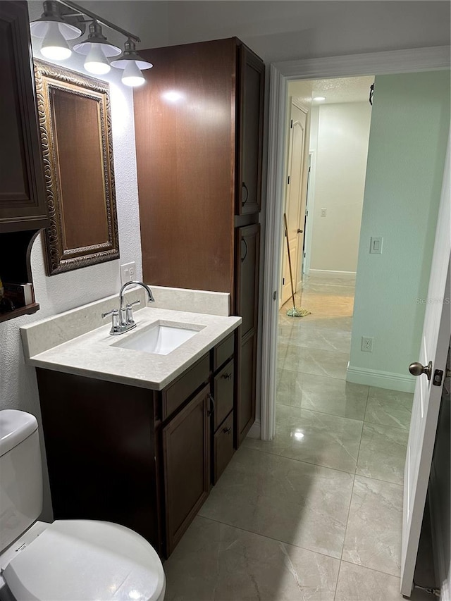 bathroom with marble finish floor, baseboards, vanity, and toilet