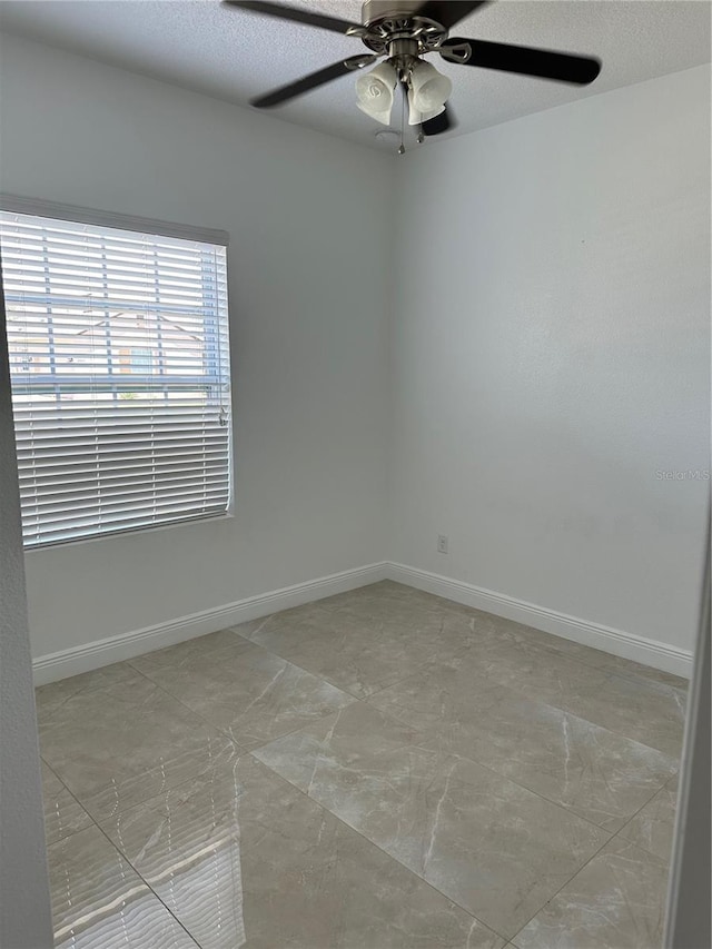 unfurnished room featuring a ceiling fan, a textured ceiling, and baseboards