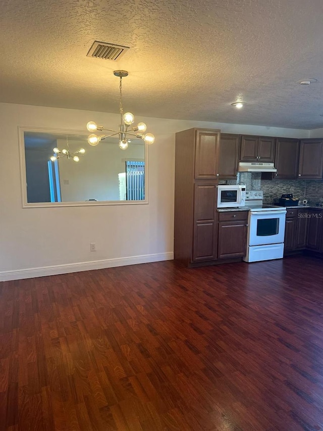 kitchen with a chandelier, under cabinet range hood, white appliances, dark wood-type flooring, and visible vents