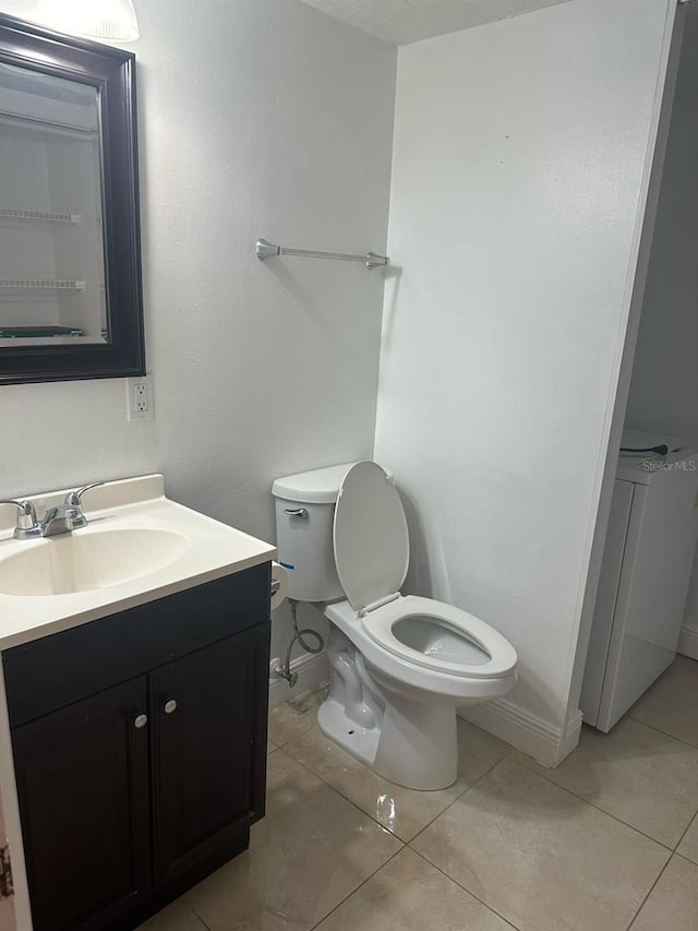 bathroom featuring toilet, tile patterned floors, washer / clothes dryer, and vanity