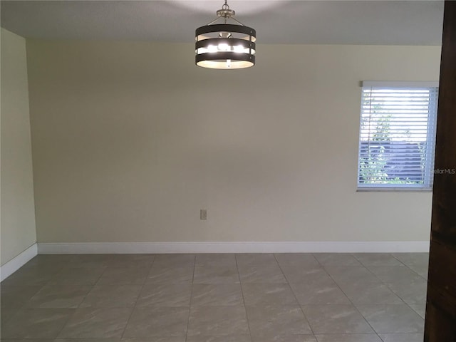 unfurnished room with tile patterned flooring and baseboards