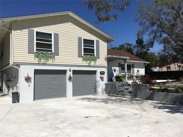 view of front of house featuring driveway, an attached garage, and brick siding