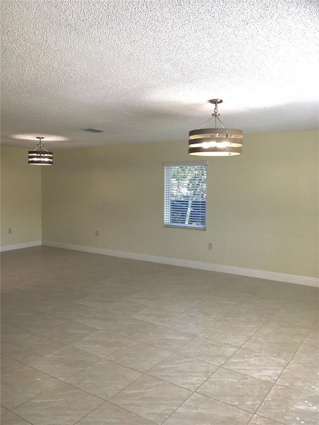 unfurnished room with a textured ceiling, visible vents, and baseboards