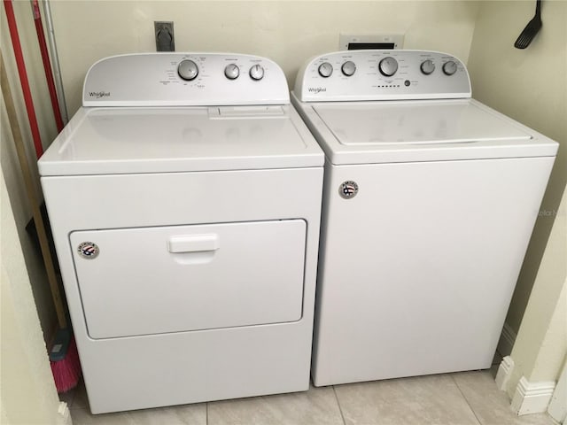 washroom featuring laundry area, washing machine and clothes dryer, and light tile patterned floors