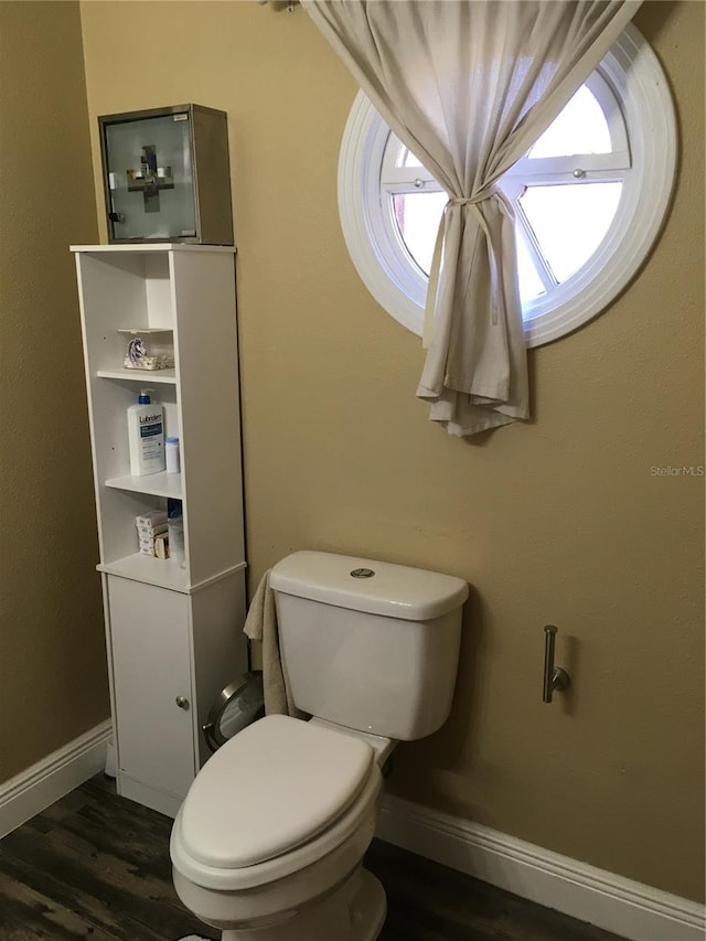 bathroom with toilet, baseboards, and wood finished floors