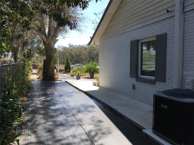 view of property exterior with a patio, fence, central AC, and brick siding