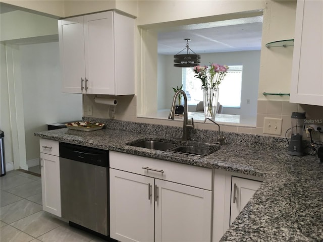 kitchen featuring tasteful backsplash, stainless steel dishwasher, white cabinets, a sink, and dark stone counters