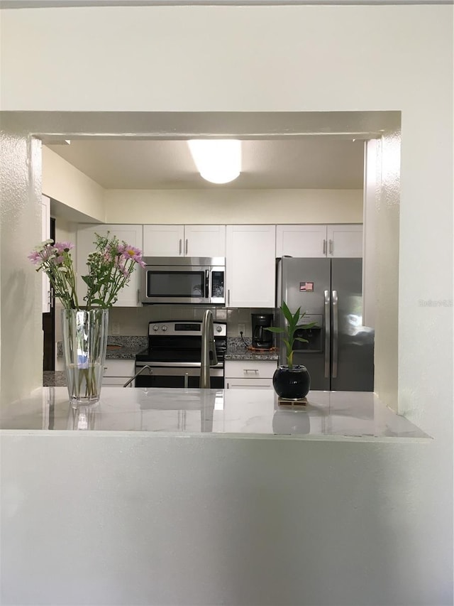 kitchen with stainless steel appliances, white cabinets, and a peninsula