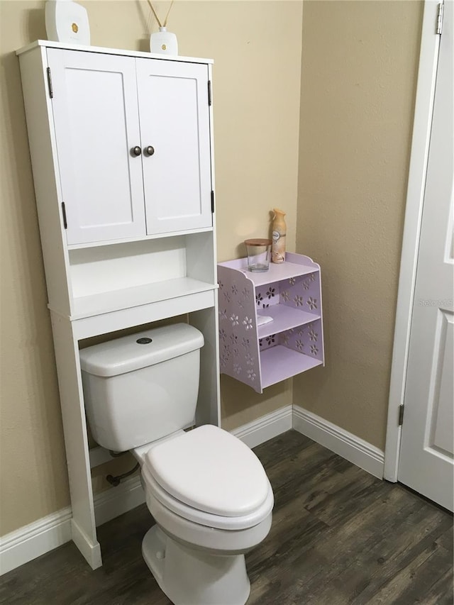 bathroom with toilet, baseboards, and wood finished floors