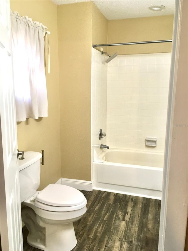 full bathroom featuring toilet, bathing tub / shower combination, wood finished floors, and baseboards