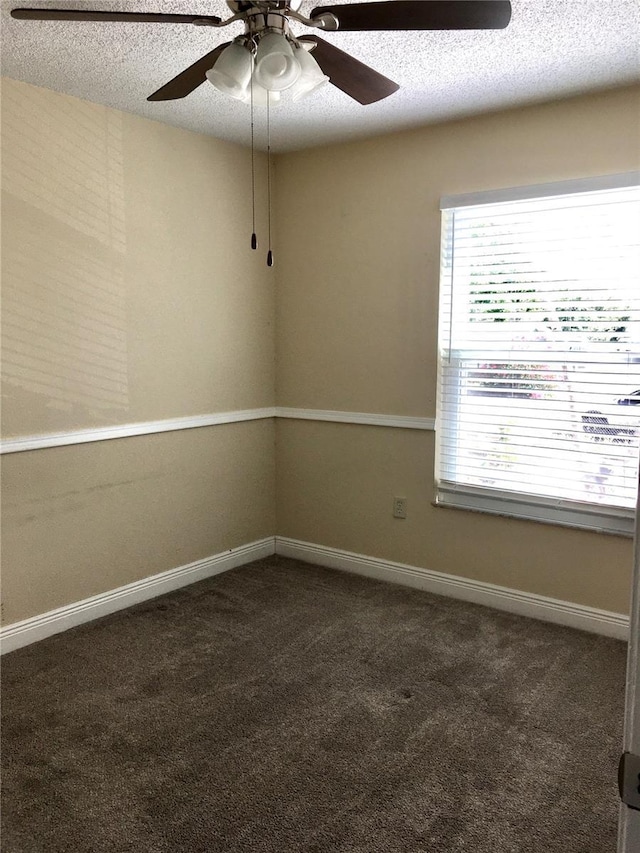spare room with baseboards, dark carpet, a ceiling fan, and a textured ceiling