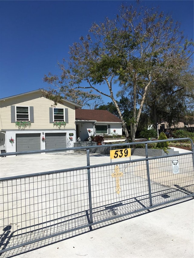 view of front facade with driveway, an attached garage, and fence