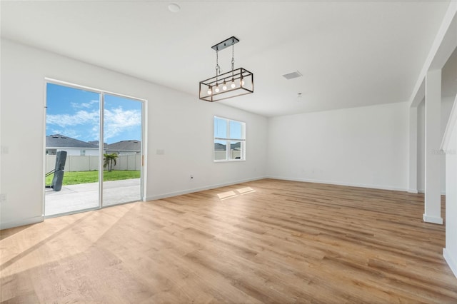 empty room featuring visible vents, light wood finished floors, a wealth of natural light, and baseboards