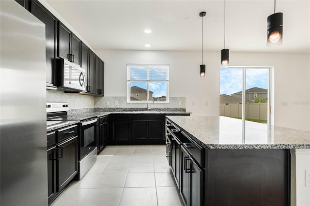 kitchen featuring a sink, appliances with stainless steel finishes, dark cabinets, and a center island