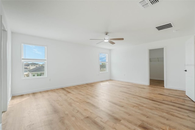 unfurnished room featuring light wood-style floors, visible vents, ceiling fan, and baseboards