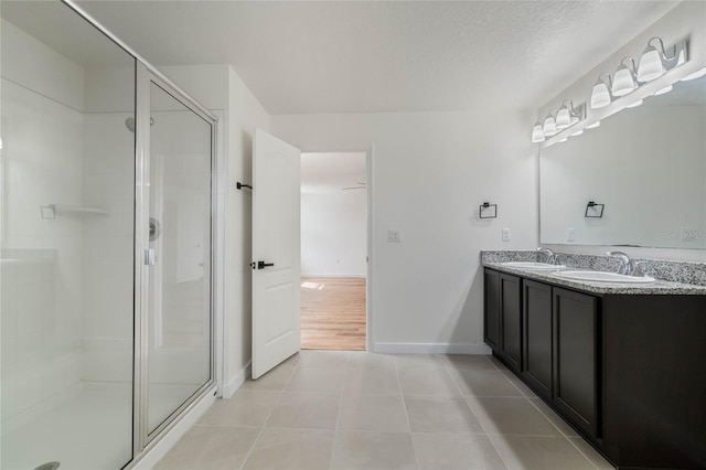 bathroom with a stall shower, tile patterned flooring, and a sink