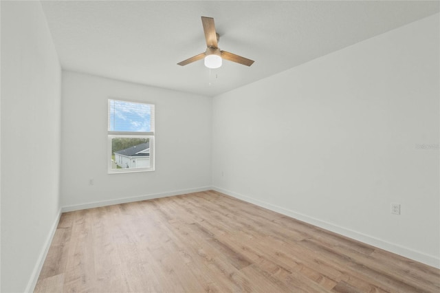 empty room featuring ceiling fan, light wood finished floors, and baseboards