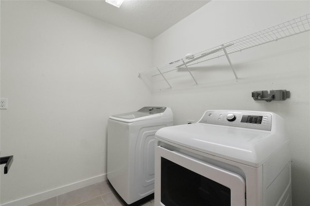 clothes washing area featuring laundry area, light tile patterned floors, baseboards, and independent washer and dryer