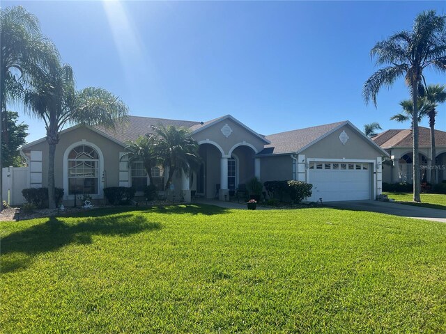 single story home featuring stucco siding, an attached garage, driveway, and a front yard