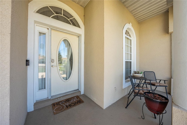 property entrance with covered porch and stucco siding