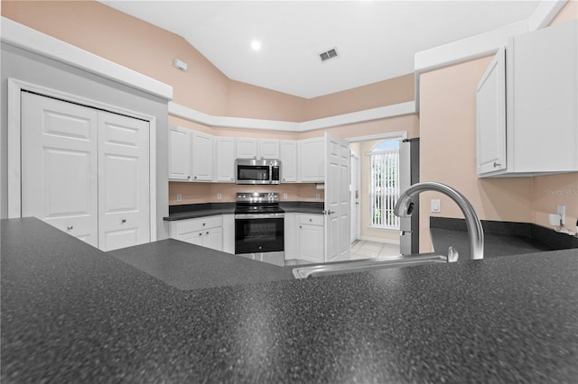 3303 Ann Arbor Ct, Saint Cloud, FL 34772 - kitchen with visible vents, a sink, vaulted ceiling, dark countertops, and appliances with stainless steel finishes