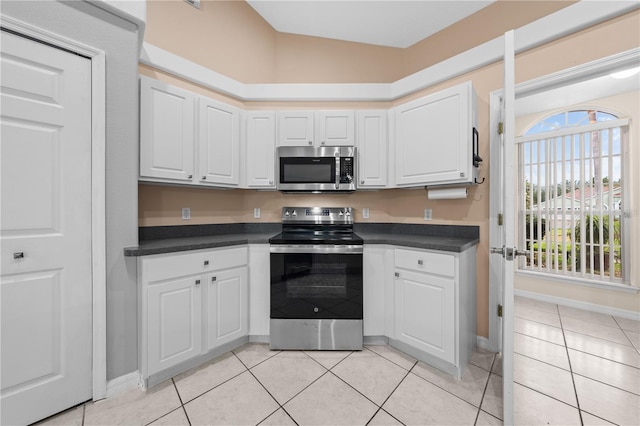 3303 Ann Arbor Ct, Saint Cloud, FL 34772 - kitchen with baseboards, light tile patterned flooring, white cabinetry, dark countertops, and appliances with stainless steel finishes