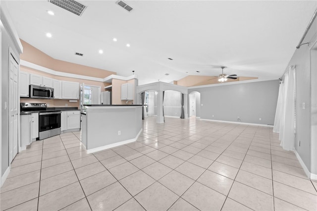 3303 Ann Arbor Ct, Saint Cloud, FL 34772 - kitchen featuring lofted ceiling, stainless steel appliances, arched walkways, light tile patterned floors, and dark countertops