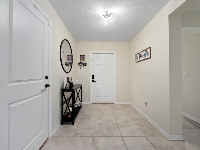 foyer featuring light tile patterned floors, a textured ceiling, and baseboards