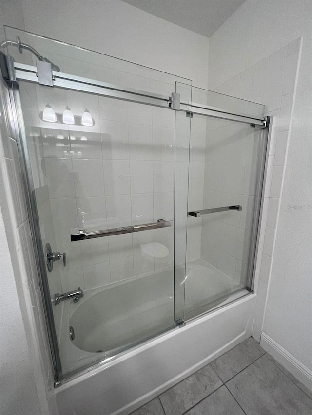 bathroom featuring bath / shower combo with glass door and tile patterned flooring