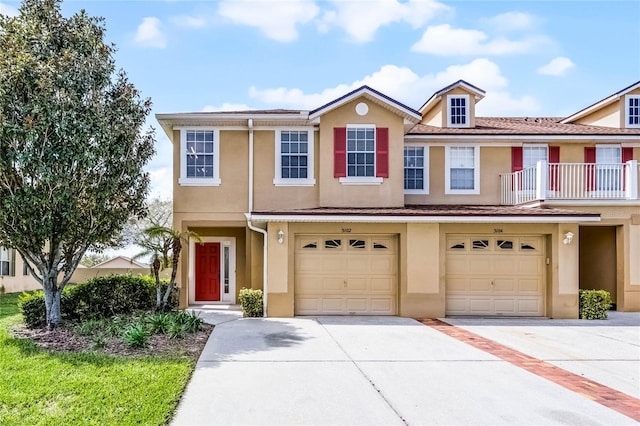 townhome / multi-family property featuring driveway, a garage, and stucco siding